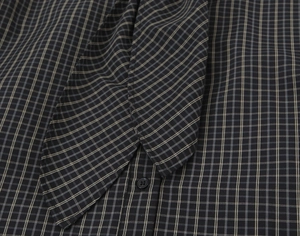 Close-up of the pussy-bow neckline and button detail on a black and white plaid shirt