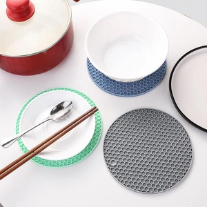 Round honeycomb silicone trivets for heat insulation in various colors on a white table