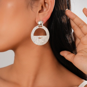 Close-up of sparkling silver geometric round drop earrings with pave diamonds on model