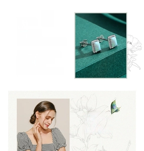 Macro detail of silver opal earrings with green fire effect on a dark green display