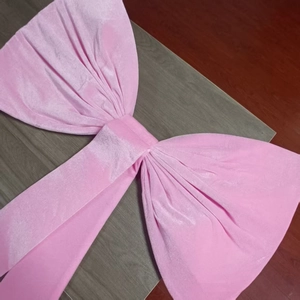Detail shot of large pink velvet decorative bow for party backdrops on a dark surface