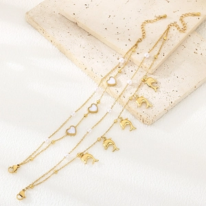 Golden stainless steel heart and dolphin charm bracelets with pearls on a stone plate