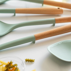 Light green food-grade silicone cooking tools with wooden handles on a white background