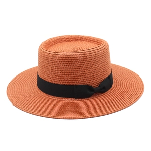 Detail of burnt orange boater hat with black ribbon bow and fine weave texture