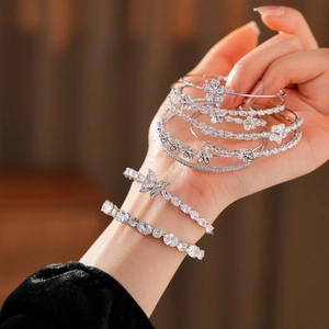 Gros plan d'un bracelet jonc à fleurs en argent et d'un bracelet papillon en cristaux