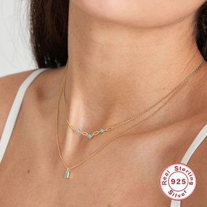 Detail of layered S925 sterling silver necklaces with turquoise moon pendants on model