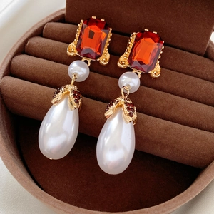 Macro detail of vintage gold pearl earrings with red gemstone and ruby accents