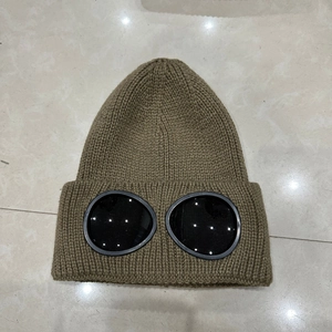 Detail view of khaki knit beanie featuring integrated black goggles and thick warm ribbed texture