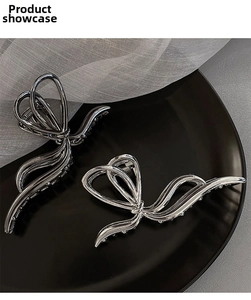 Detail of silver butterfly hair clips in two sizes on a sleek black decorative plate