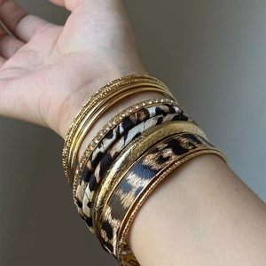 Ten-piece set of gold metal and leopard print leather bangles with sparkling rhinestones