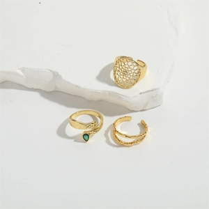 Three gold-plated open rings including floral patterns and a green teardrop gemstone snake ring
