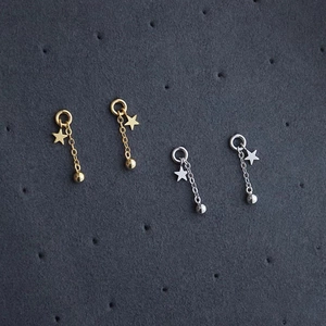 Detailed view of gold and silver star tassel drop earrings on a textured grey surface