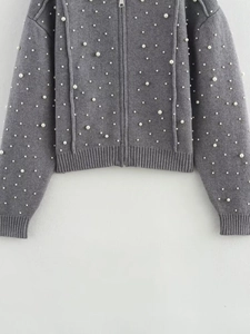 Close-up of gray knitted bomber jacket featuring white pearl beads and metal zipper detail