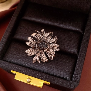 Close-up of vintage sunflower ring with textured metal petals in a black silk jewelry box