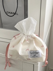 Close-up of cream fabric tissue pouch featuring pink bow patterns and a stitched label
