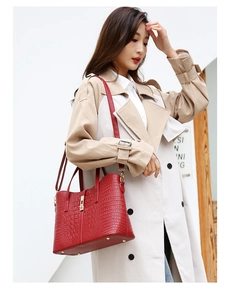 Detail of burgundy crocodile pattern tote bag with metal buckle and glossy finish