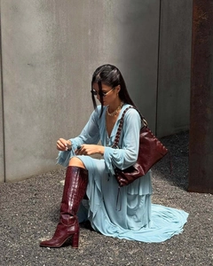 Detail of bohemian light blue ruffle dress paired with dark red croc-embossed tall boots