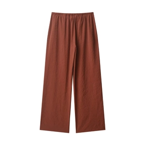 Detail shot of tan wide-leg trousers showing lightweight textured fabric with natural folds