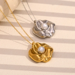 Close-up of gold and silver flower necklaces with pearls on a textured background