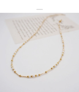 Detail of elegant pearl necklace with gold-tone tubes on a minimalist white background