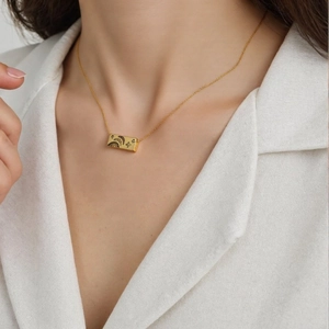 Detail of 18K gold plated rectangular pendant featuring moon and star engravings