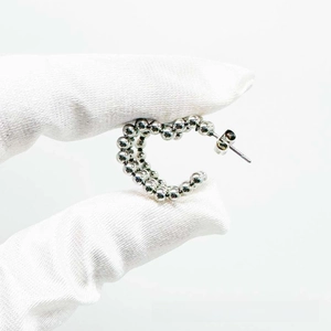 Detail of C-shaped hoop earrings with silver metal beads shown on a white background