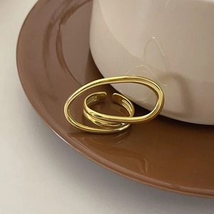 Detail of a golden multi-layer twisted geometric open ring on a warm brown display plate