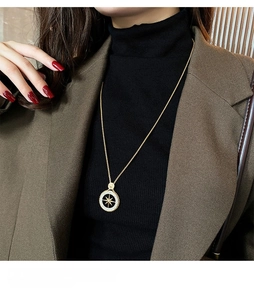 Detailansicht der goldene achteckige Sternkette mit Zirkonia auf schwarzem Pullover