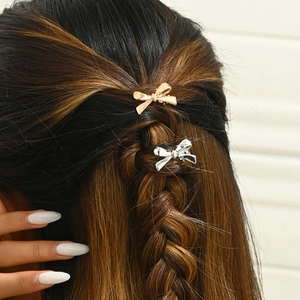 Polished silver and rose gold metal bow hair clips on brunette braided hair for women