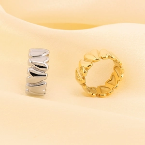 Close-up of gold and silver heart-shaped open rings on elegant yellow silk background