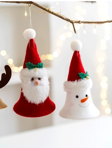 Detail of fabric Santa and Snowman ornaments with bells hanging on a warm lit branch
