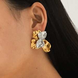 Two-tone hammered metal flower earrings in gold and silver finish worn by a model