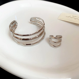 Close-up of triple-layered silver bamboo style cuff bracelet and ring set in a white tray