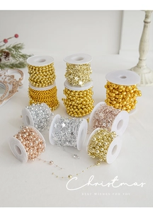 Detail of gold and silver Christmas star bead garlands on rolls for festive DIY decor
