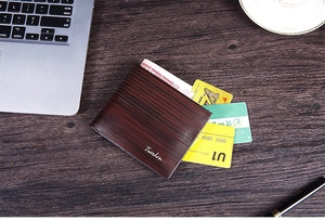 Short brown bifold wallet with wood grain texture and card slots on office desk