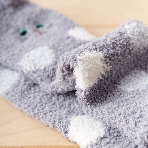 Close-up of soft grey coral fleece socks with white polka dots and animal embroidery