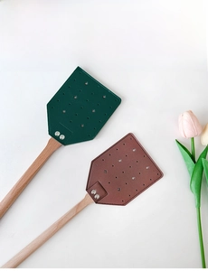 Close-up of leather fly swatter head with wood handle and reinforced metal rivets