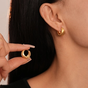 Minimalist matte gold geometric hoop earrings shown on a hand and worn by a model