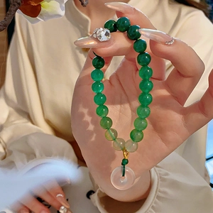 Detail of green jade beaded bracelet with a vintage donut pendant and gold accents