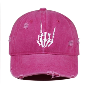 Detailed close-up of pink distressed baseball cap with white skeleton hand embroidery