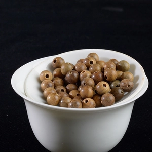 Close-up of polished 8mm green sandalwood beads with natural wood grain in a white cup