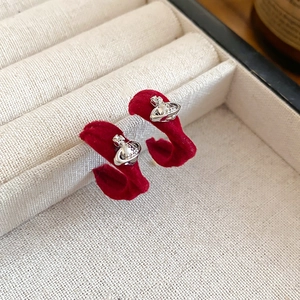 Détail de boucles d'oreilles en velours rouge avec emblème planète argenté en écrin
