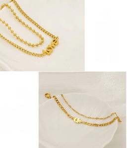 Detail of gold-plated stainless steel LOVE necklace and Hamsa hand layered bracelet set
