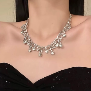 Elegant silver necklace set with teardrop diamond pendant worn by a model in black dress