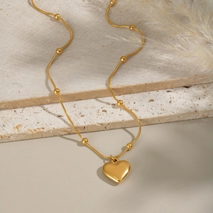 Collier élégant doré avec pendentif cœur et chaîne à billes sur support minéral