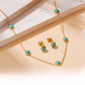 Detail of vintage gold-plated necklace and turquoise earrings on natural stone