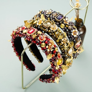 Close-up of luxury velvet headbands with intricate beadwork and rhinestones on a gold stand