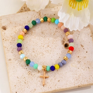 Detail of colorful crystal beaded bracelet with a polished gold cross pendant charm