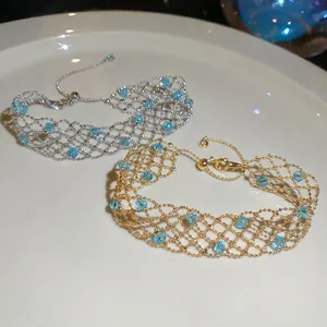 Elegant gold and silver mesh bracelets with blue crystal beads in a white ceramic dish