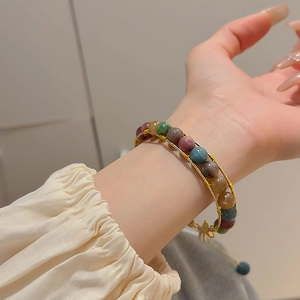 Detail of vintage beaded bracelet with tiger eye stones and a gold star charm pendant
